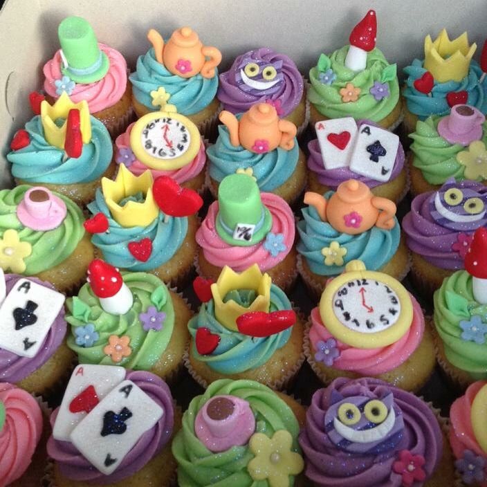 there are many cupcakes in the box with colorful frosting on them,