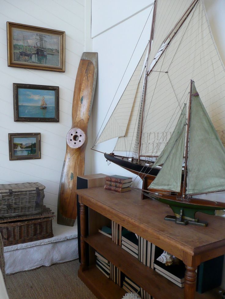 a model sailboat sitting on top of a wooden table next to a book shelf