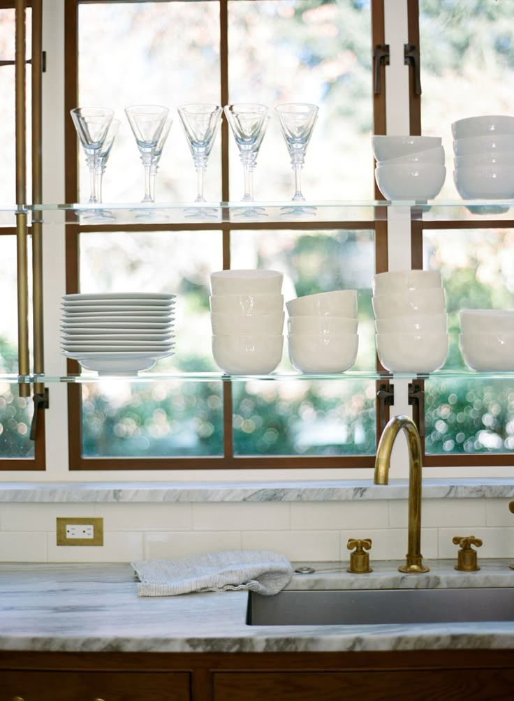 the kitchen sink is full of dishes and glasses in front of a window with glass panes on it