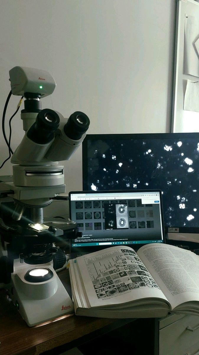 a laptop computer sitting on top of a desk next to a microscope and a book