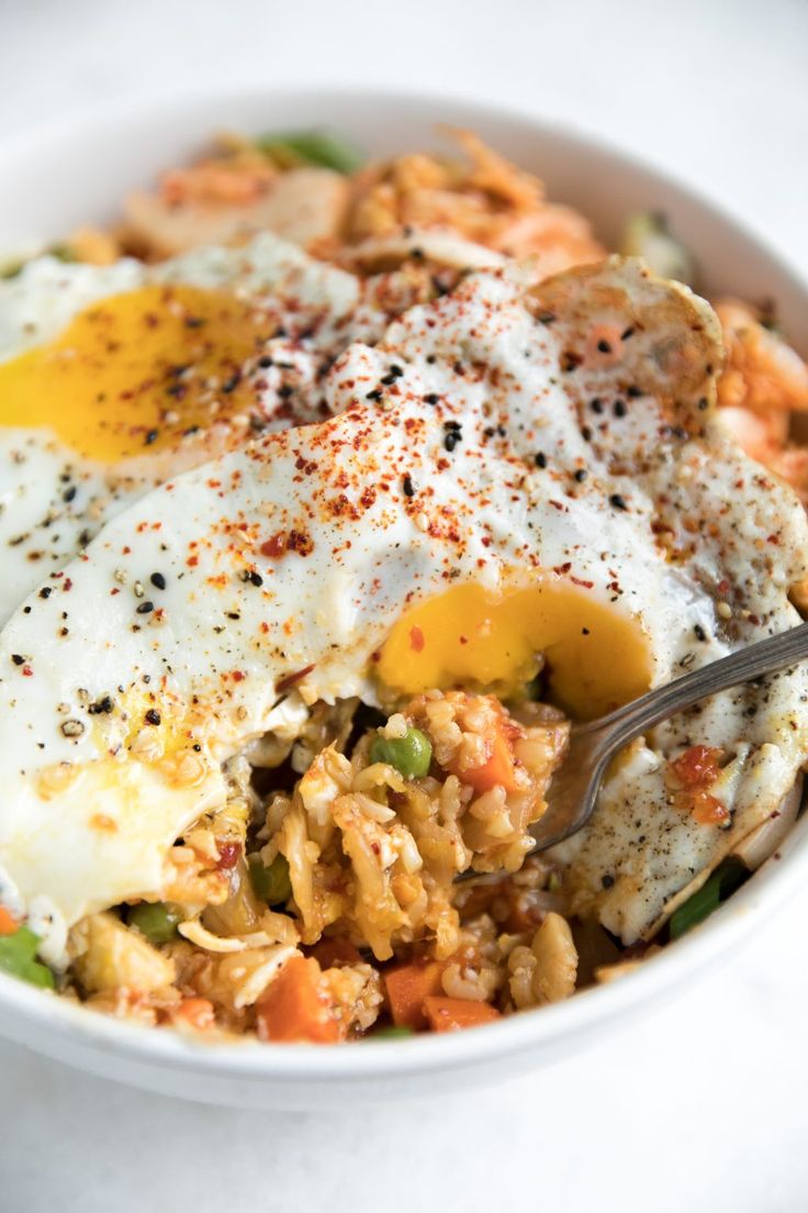 a white bowl filled with rice and fried eggs