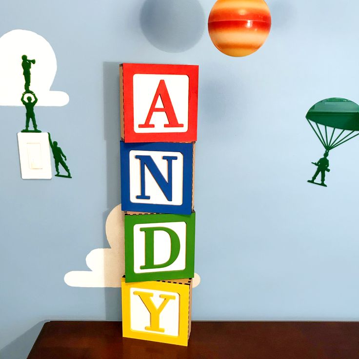 a wooden block with the word andy spelled in it and an orange ball hanging from the wall