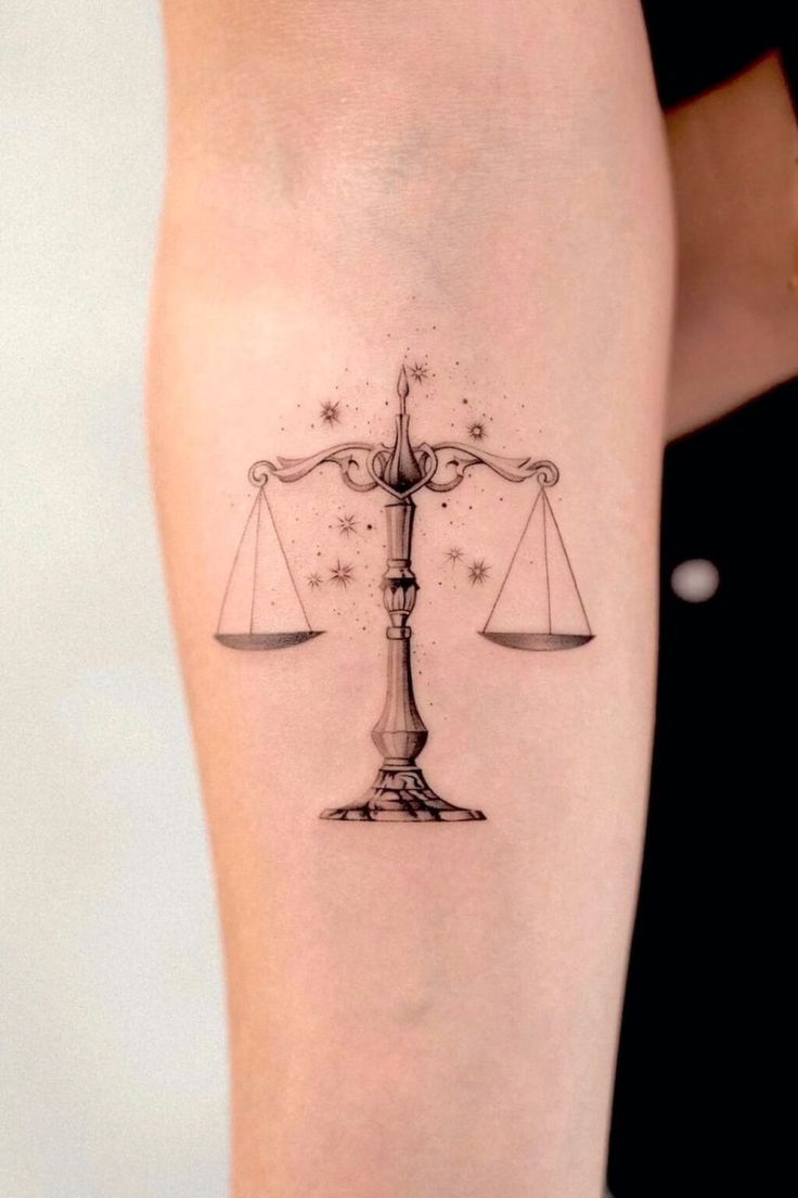 a woman's leg with a tattoo on it that has a scale and stars