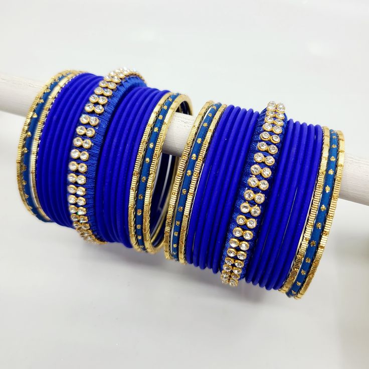 Bangle set comes with 2 sets - 1 per arm. Step into a realm of regal charm with our stunning royal blue bangles, accompanied by a captivating centre thread bangle adorned with diamond zircon stones. The deep and lustrous royal blue hue exudes a sense of grandeur and sophistication, making a bold statement wherever you go. The centre thread bangle adds a touch of artistry and delicacy, beautifully enhanced by the glistening diamond zircon stones, which add a mesmerizing sparkle to the ensemble. E Blue Bangle Bracelet For Wedding, Blue Bangle Bracelets For Wedding, Blue Stone Work Jewelry For Celebration, Adjustable Hand Set Bangle For Celebration, Blue Bracelets For Festivals, Adjustable Hand-set Bangle For Celebrations, Blue Bangle For Party And Festivals, Blue Bangle For Festivals And Party, Blue Bracelets For Party And Festivals