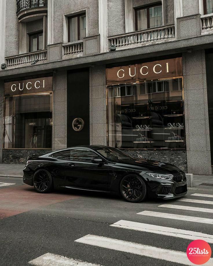 a black car parked in front of a gucci store