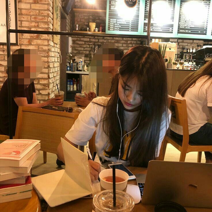 a woman sitting at a table with a laptop and headphones in front of her