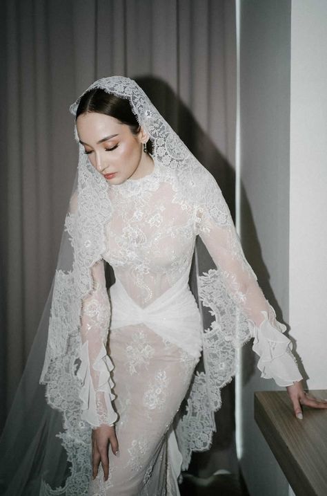 a woman in a white wedding dress with a veil on her head is leaning against a wall