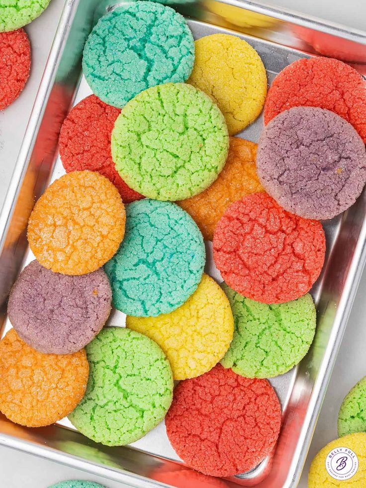 colorful cookies are in a tin on the table