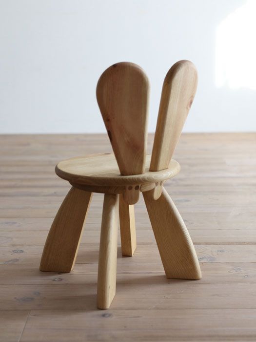 a wooden chair with two spoons on it's legs and one in the middle