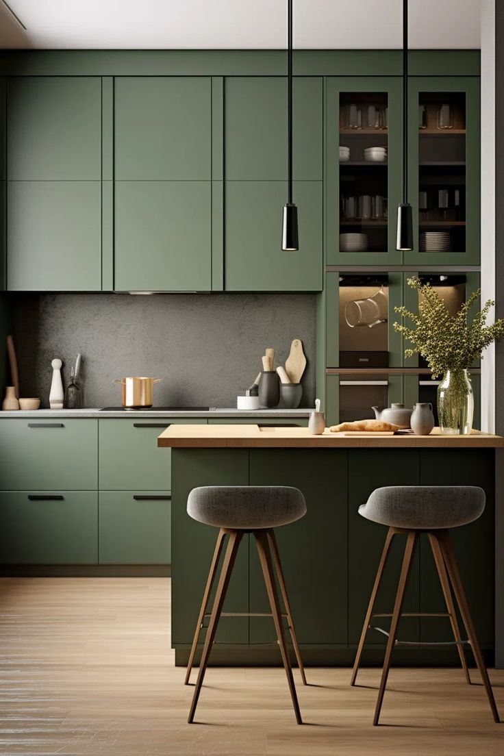 two stools sit in front of the kitchen island with green cabinets and counter tops