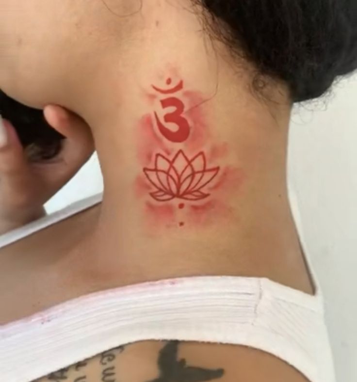 the back of a woman's neck with a lotus tattoo on her left side