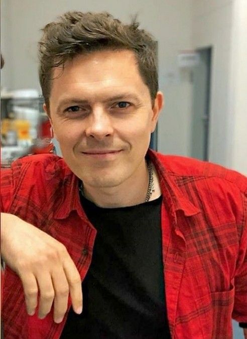 a man in a red shirt posing for the camera