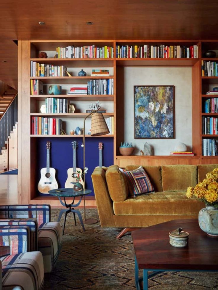 a living room filled with lots of furniture and bookshelves full of books next to a stair case