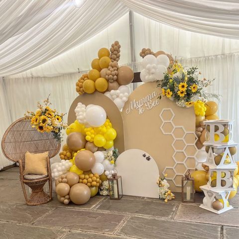 a decorated stage set up with balloons, flowers and honeycombs for a baby's first birthday