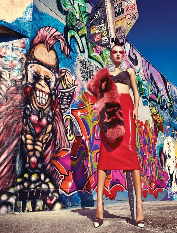 a woman standing in front of a wall with graffiti on it