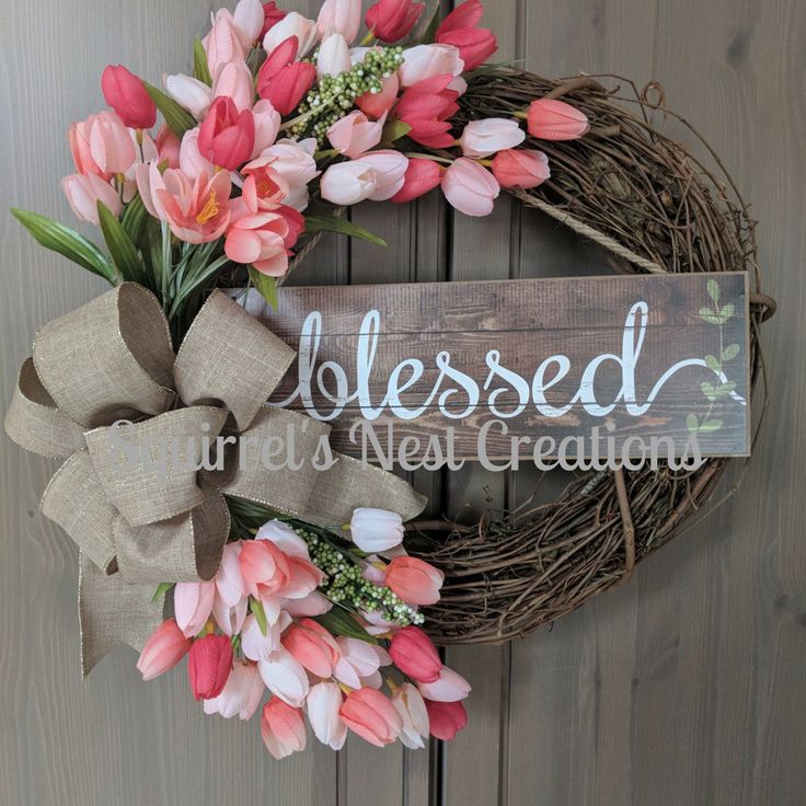 a wreath with pink flowers and a wooden sign that says, blessed