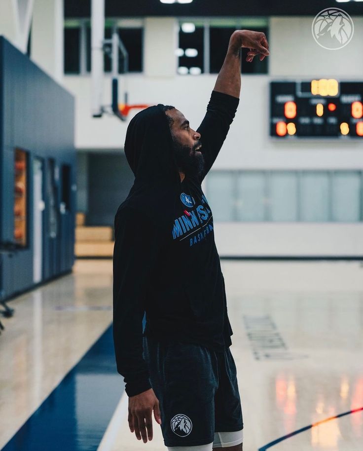 a man in a black hoodie throwing a basketball up to the air with his right hand