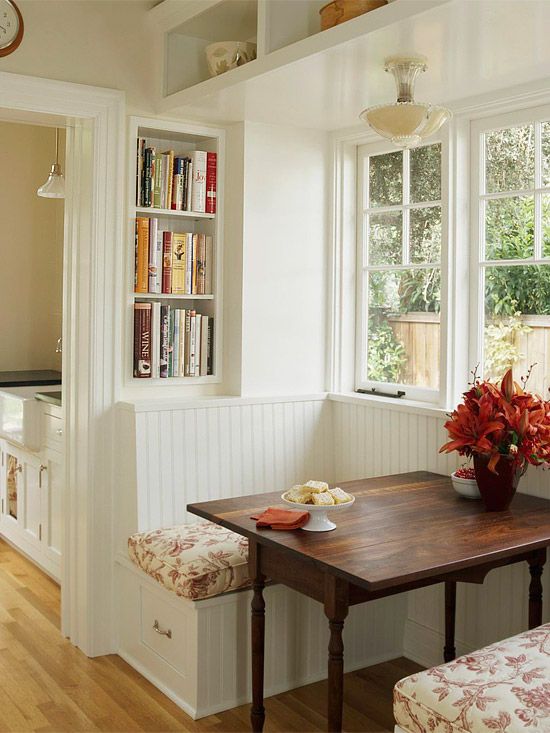 a dining room table with two chairs and a bench in front of the window next to it