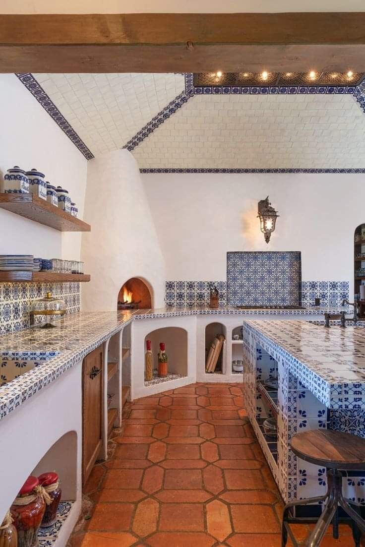 a kitchen with blue and white tiles on the walls, counter tops and ovens