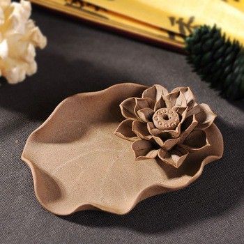 a flower shaped dish sitting on top of a table next to some pine cones and flowers