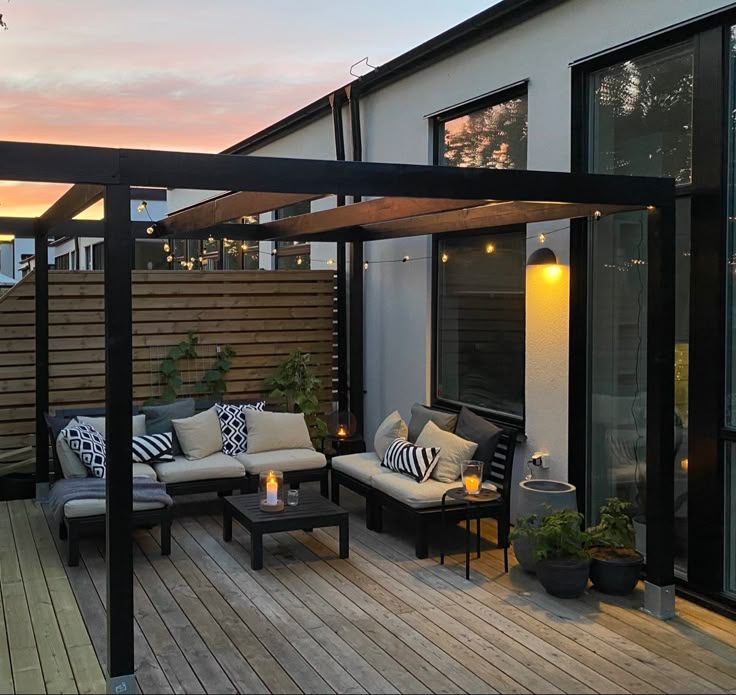 an outdoor living area with couches, tables and lights on the deck at dusk