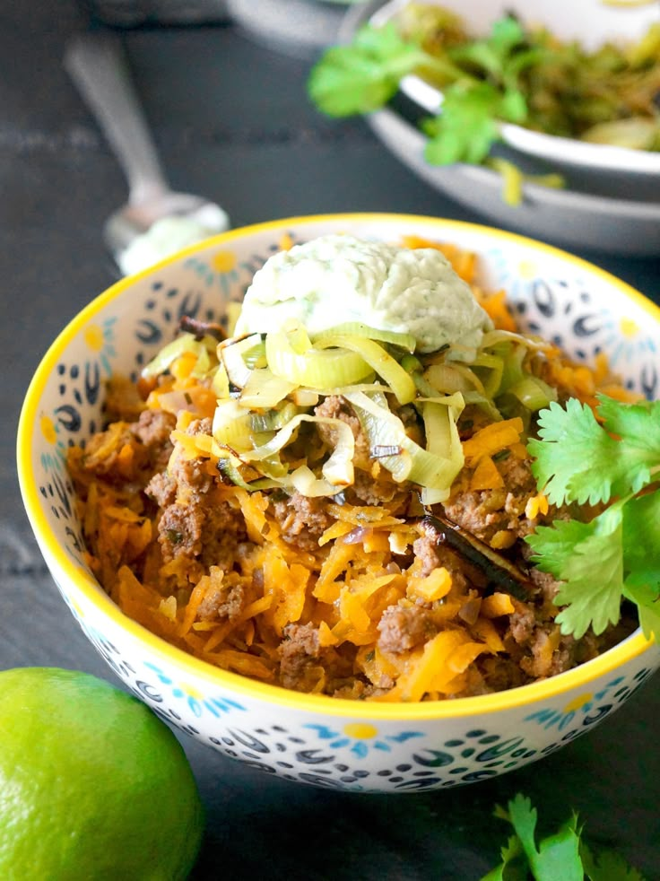 a bowl filled with mexican food next to a lime