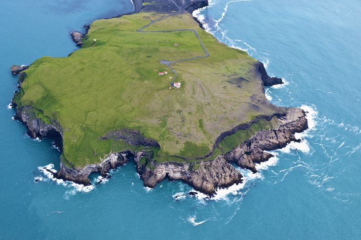 an island in the middle of the ocean surrounded by green land and blue water is shown from above