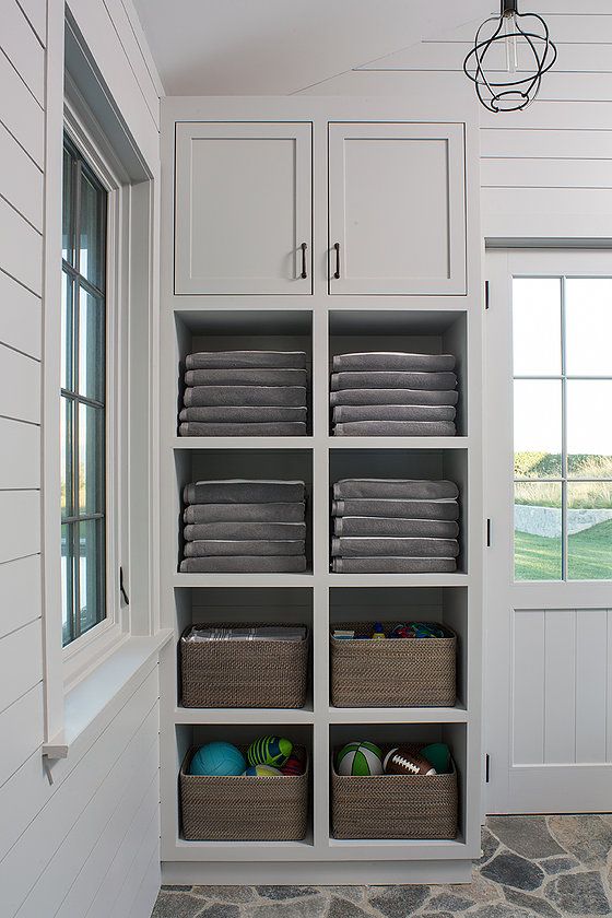 a white closet filled with lots of gray towels and other items next to a window