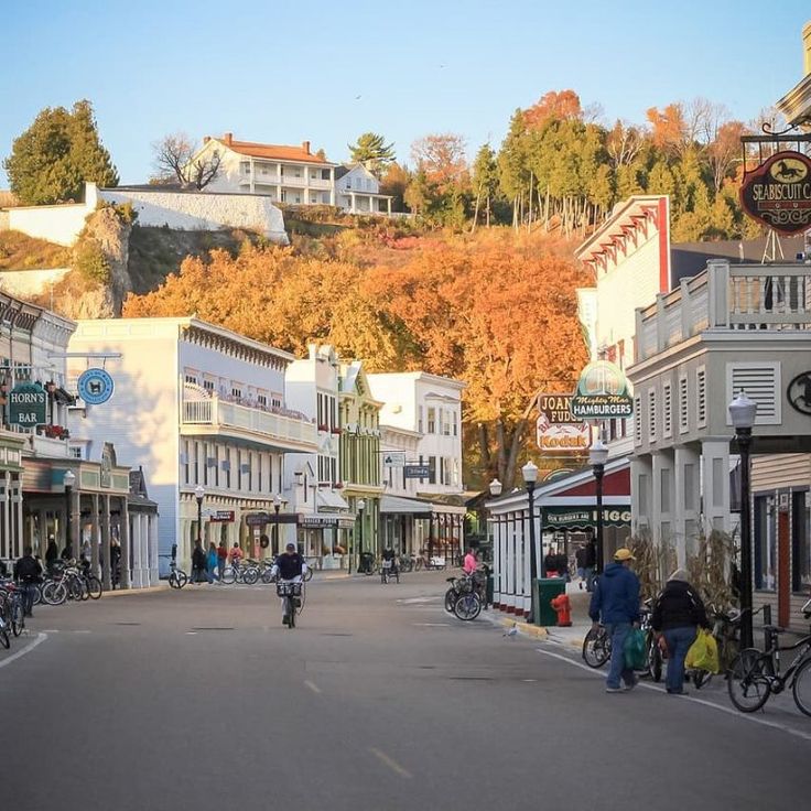 people are riding bikes down the street in front of shops and buildings on a hill