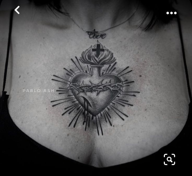 a woman's chest with a cross and heart tattoo on the top of it