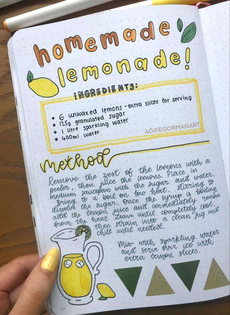 someone is holding up a notebook with some writing on the pages and an image of lemonade