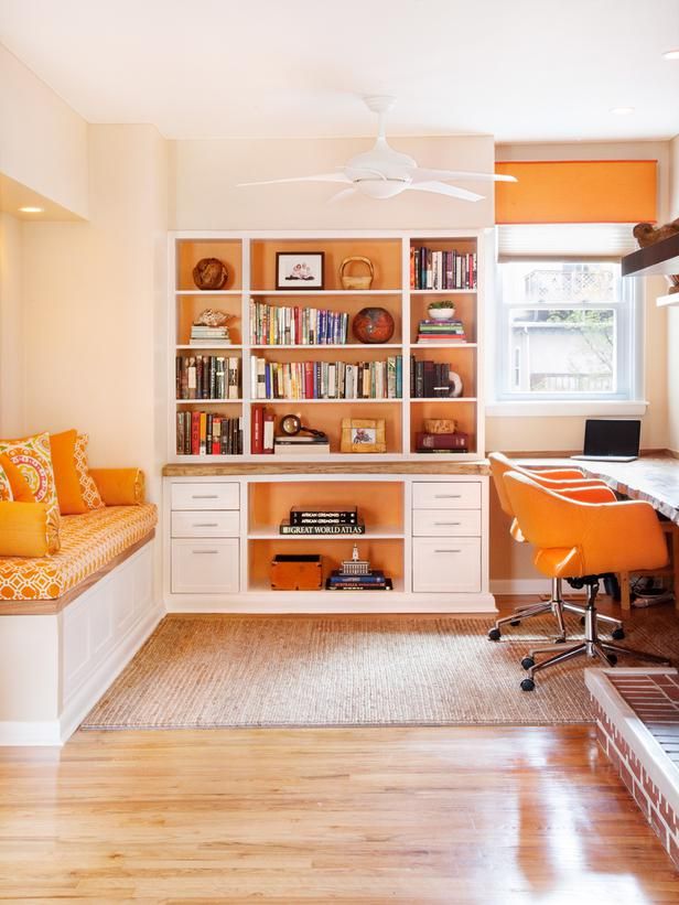 an orange and white home office with built in bookshelves, window seat, and desk