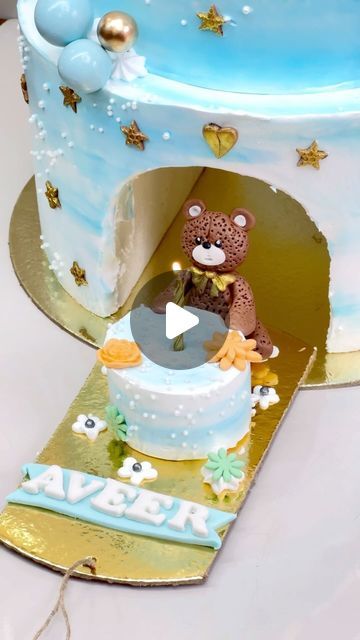 a blue and gold cake with a teddy bear on top