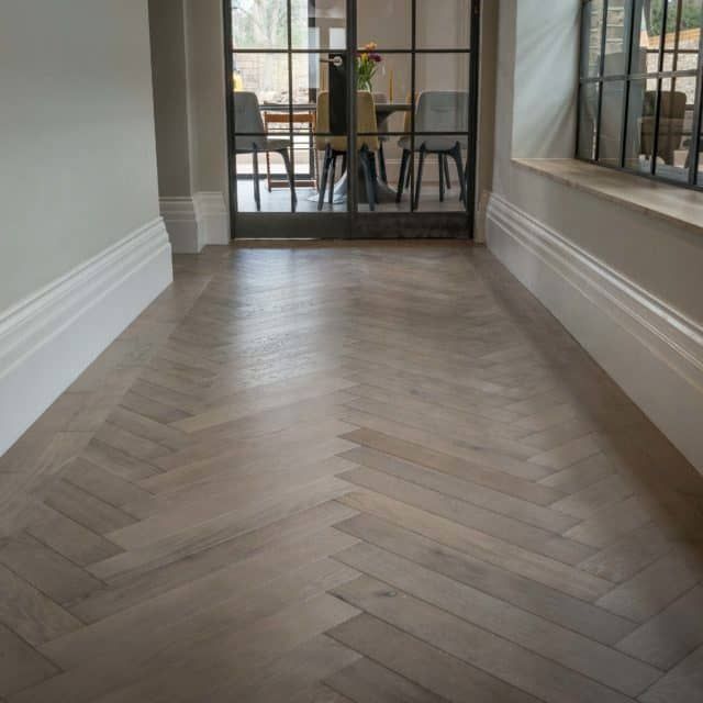 an empty room with wood flooring and glass door leading into the dining room area