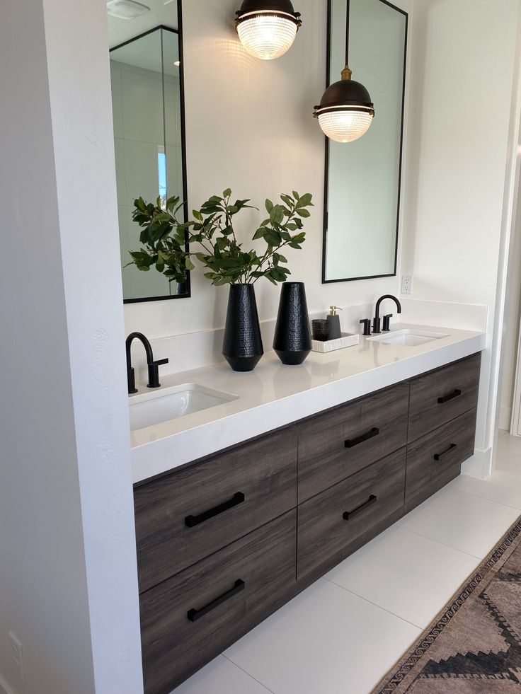 two black vases are sitting on the counter in this modern bathroom with double sinks and mirrors