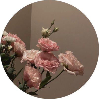 some pink flowers are in a vase on a white table top with a mirror behind them