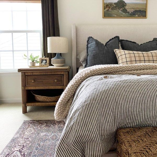 a bedroom with a bed, nightstand and window in the corner that has a painting on the wall