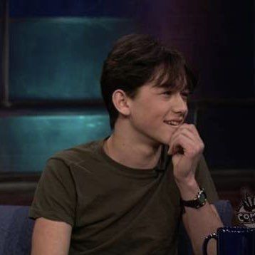 a young man sitting in front of a blue coffee mug