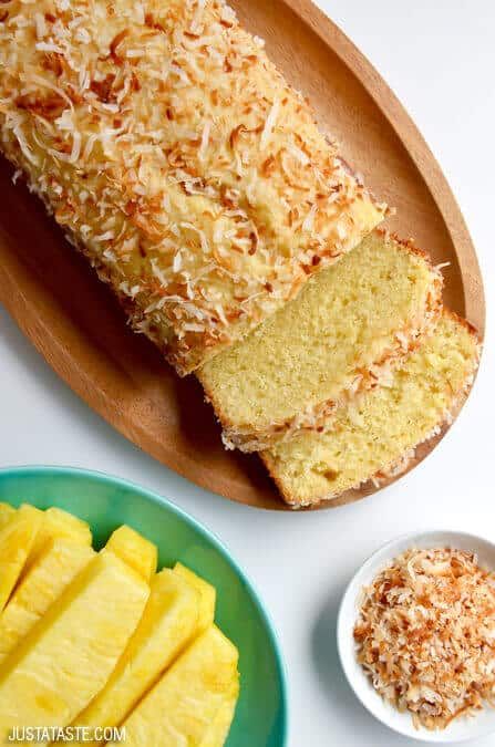 a loaf of coconut bread on a wooden plate next to two bowls of pineapples