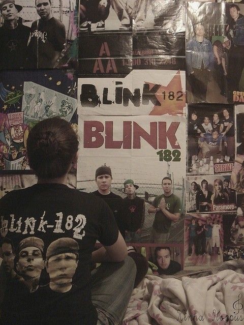 a woman sitting on top of a bed covered in posters