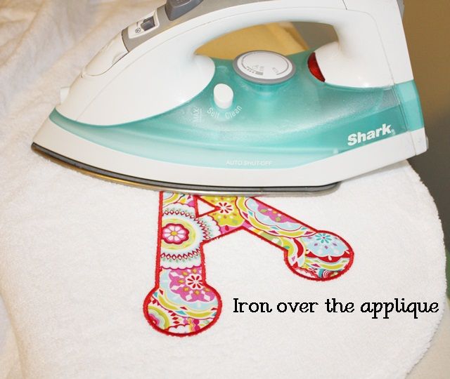 an iron on top of a towel with the letter h next to it that says, iron over the applique