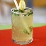 a glass filled with lemonade and lime on top of a red tablecloth covered table