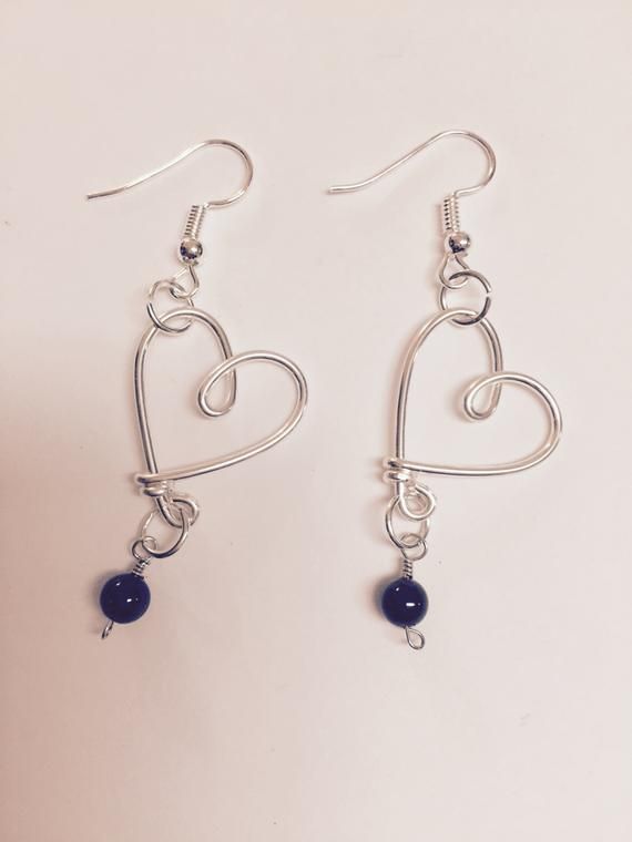 two heart shaped earrings with blue beads hanging from the ear wires on a white background