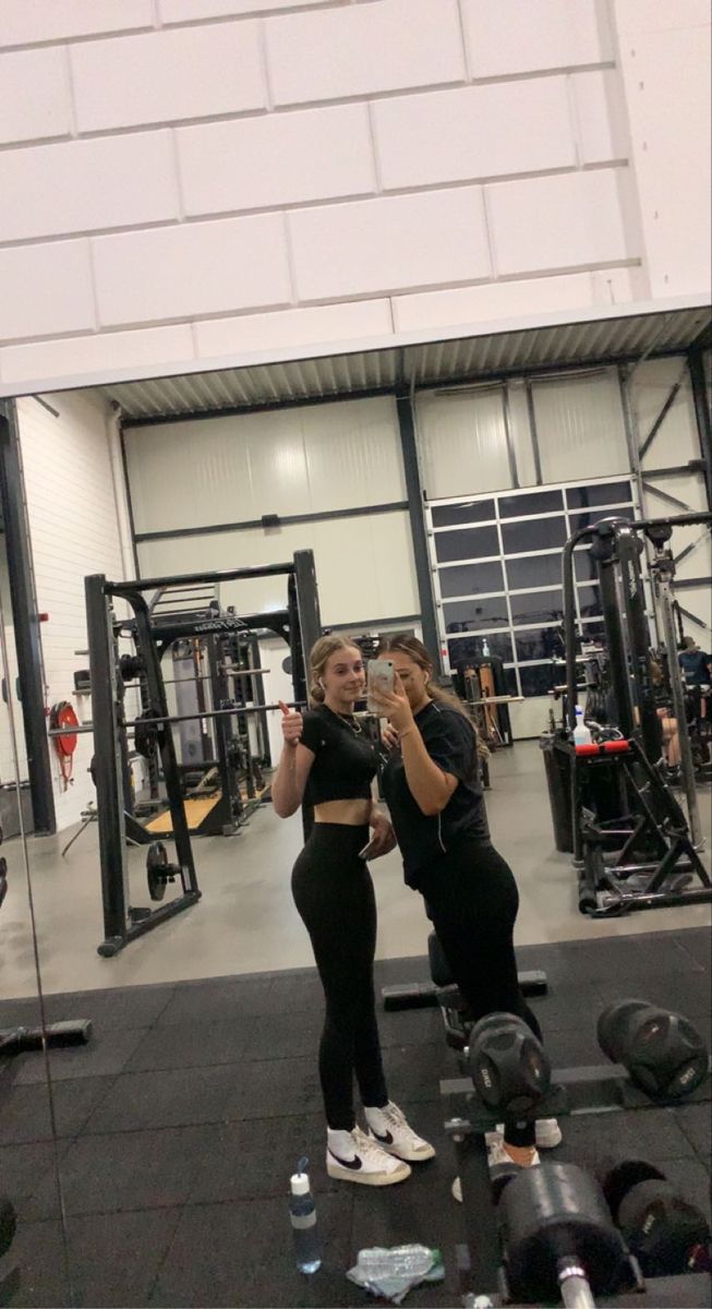 two women standing in front of a gym machine