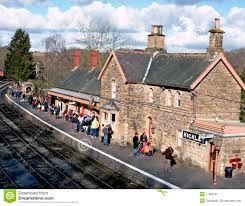 a train station with people waiting for the train to arrive and go out on the tracks