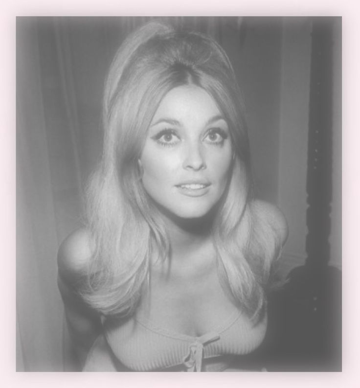 a black and white photo of a woman with long blonde hair looking at the camera