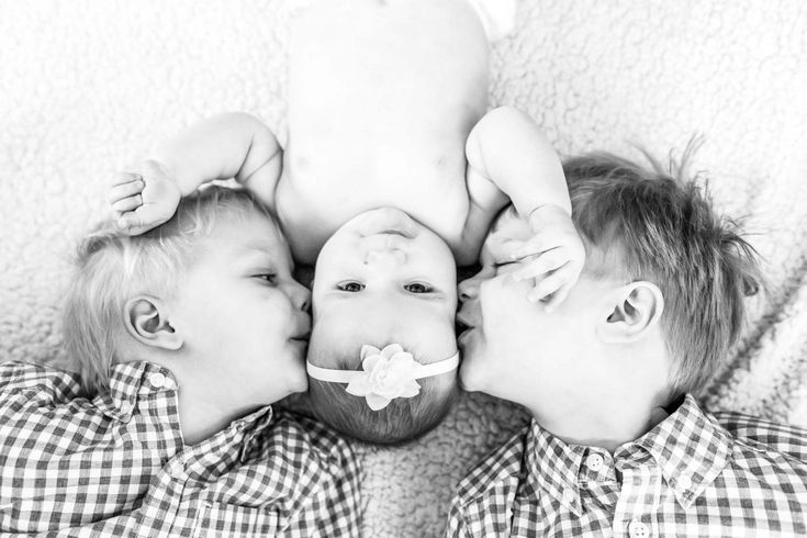 three young children are laying on the floor and one is holding his head up to their face