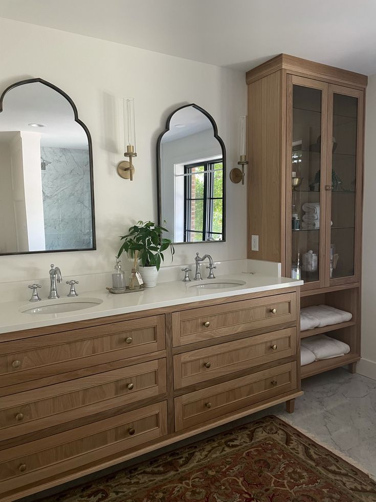 a large bathroom with two sinks and mirrors on the wall next to a rug in front of it