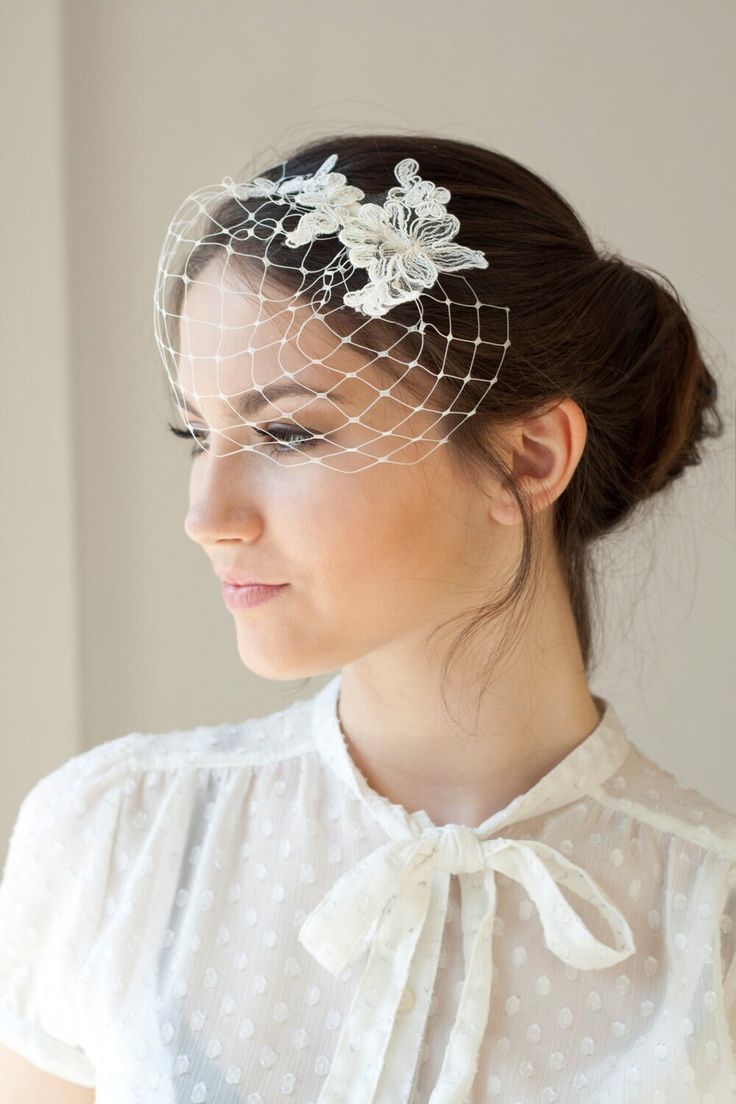 a woman wearing a white veil with flowers on the top and a birdcage over her head