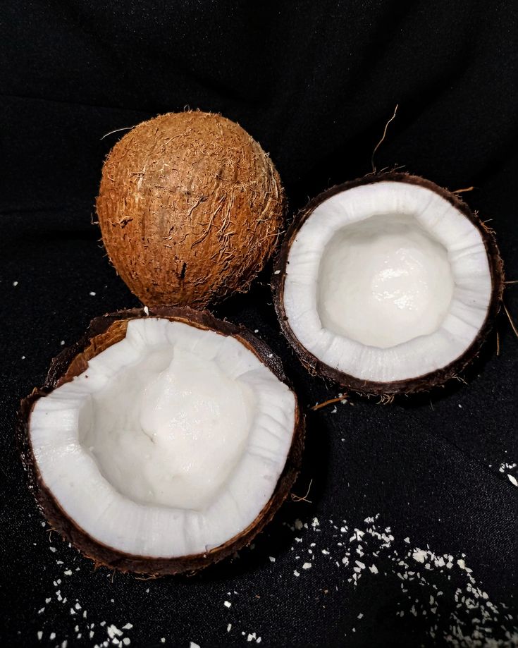 three coconuts with white stuff on them sitting next to each other in front of a black background